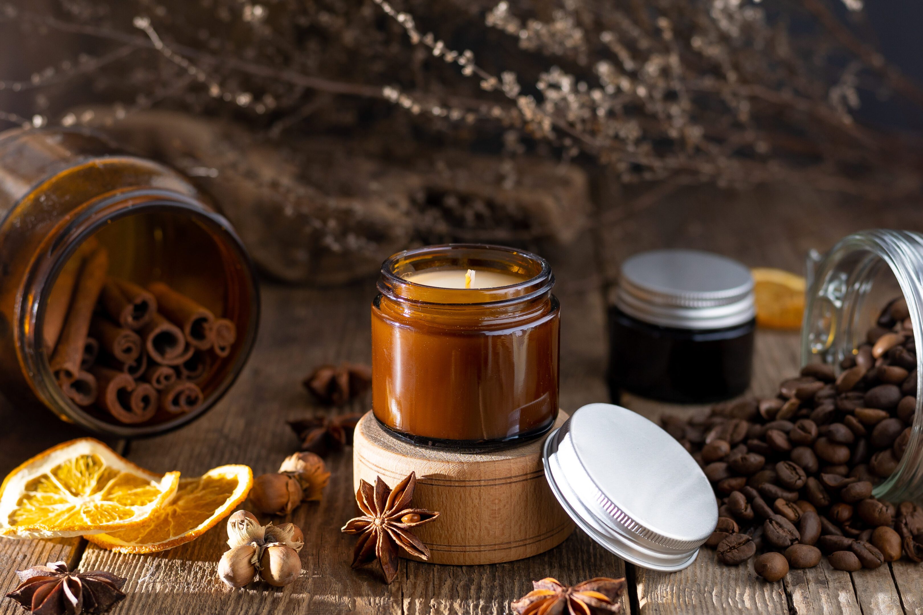 Scented candle in a glass jar. Coffee aroma. Star anise, cinnamon sticks, dried orange. Still life. Coffee beans. Brown jars with candles. Aromatherapy and relax.